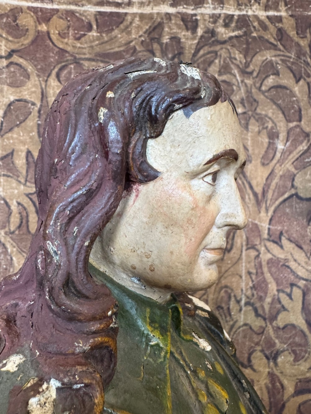 A polychrome painted bust depicting John Milton with long brown hair, a collared shirt with tassels, and a grey socle pedestal base. View VIII
