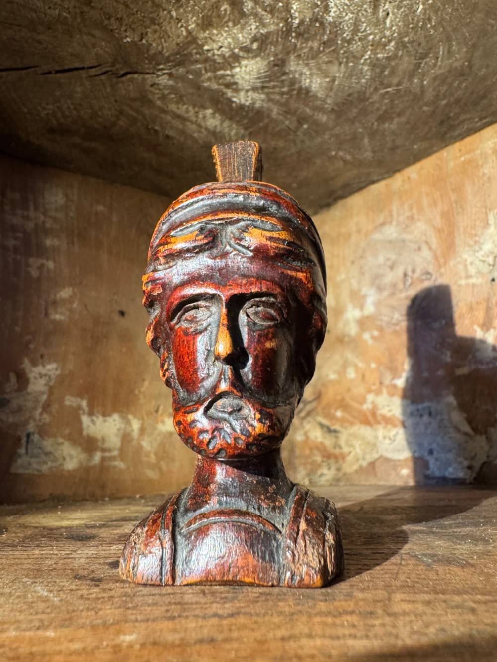 A hand-carved dark wood bust depicting a bearded warrior wearing a crested classical helmet in profile. View II