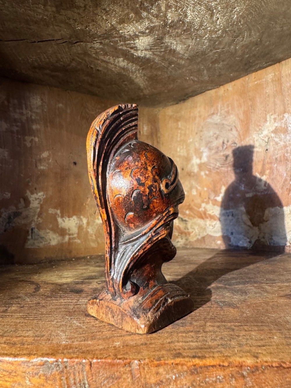 A hand-carved dark wood bust depicting a bearded warrior wearing a crested classical helmet in profile. View VI