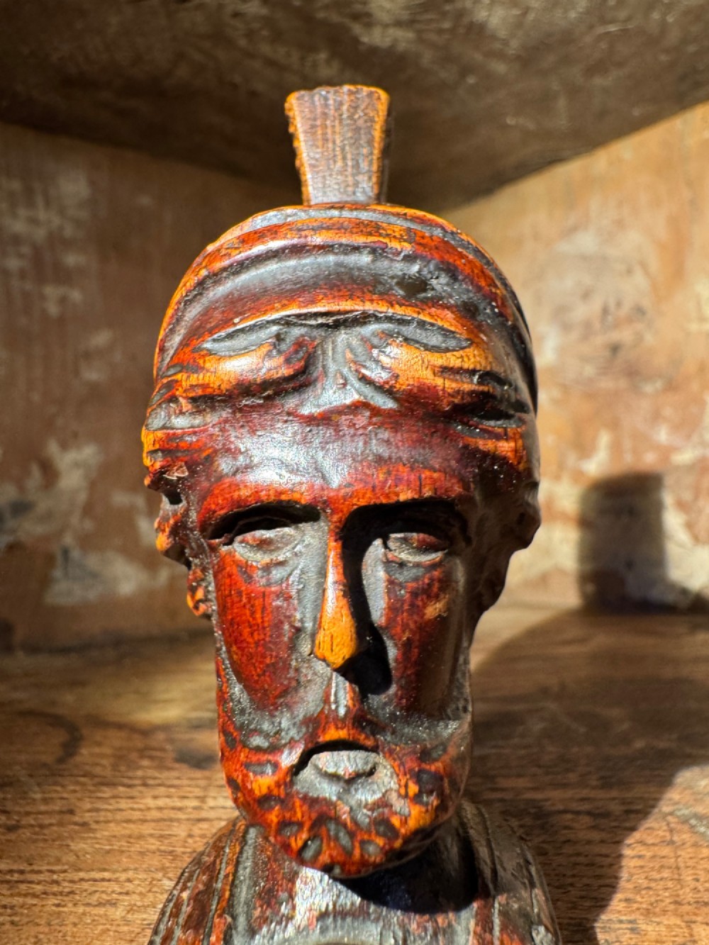 A hand-carved dark wood bust depicting a bearded warrior wearing a crested classical helmet in profile. View VIII