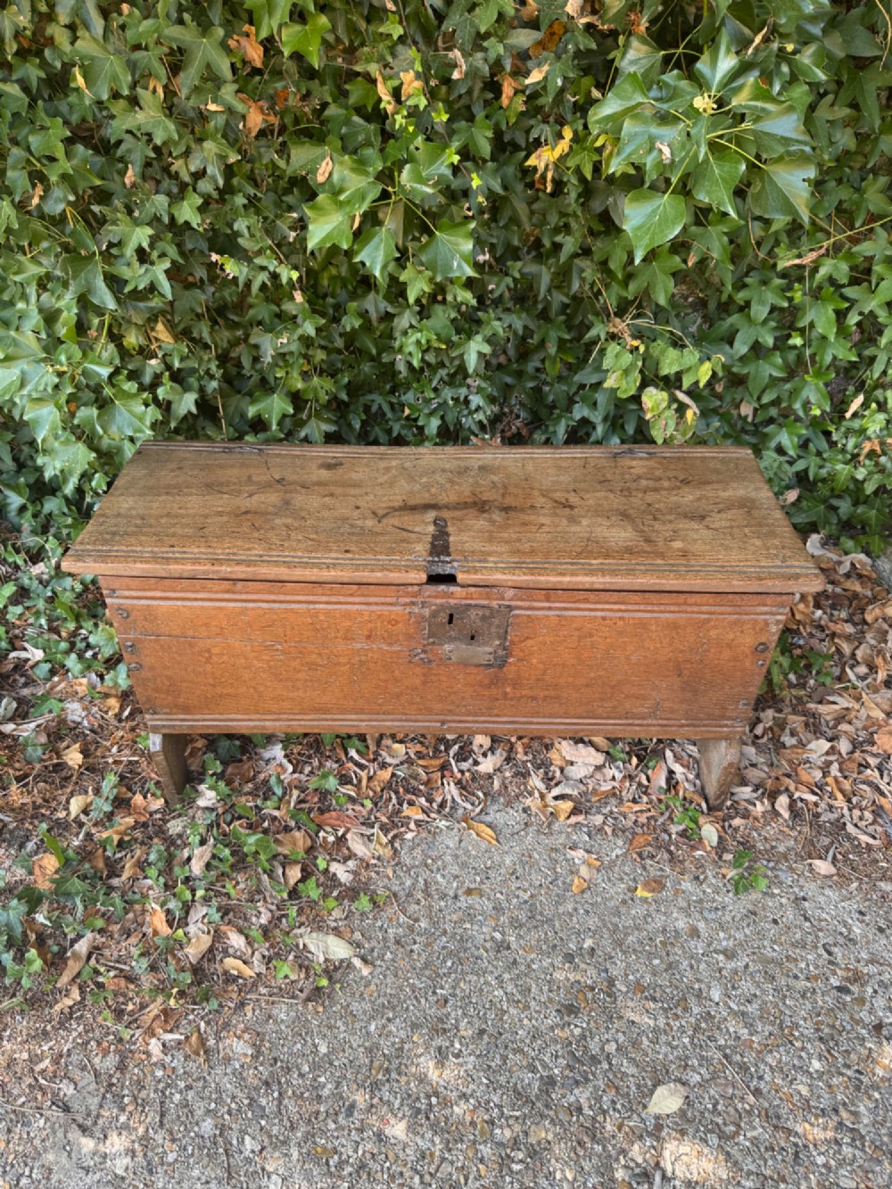An early oak plank coffer featuring notched end panels, a hinged lid, horizontal moulding, and an iron lockplate. View IV