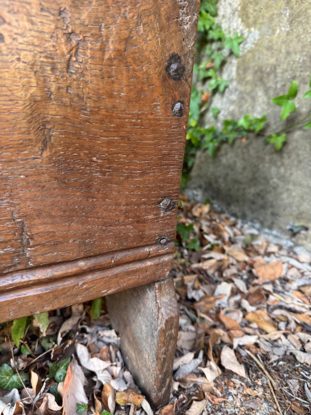 An early oak plank coffer featuring notched end panels, a hinged lid, horizontal moulding, and an iron lockplate. View VI