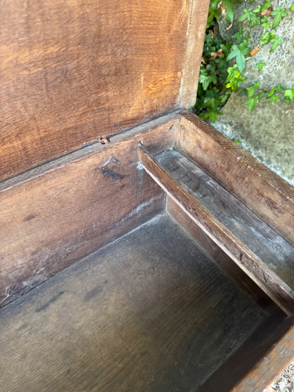 An early oak plank coffer featuring notched end panels, a hinged lid, horizontal moulding, and an iron lockplate. View VIII