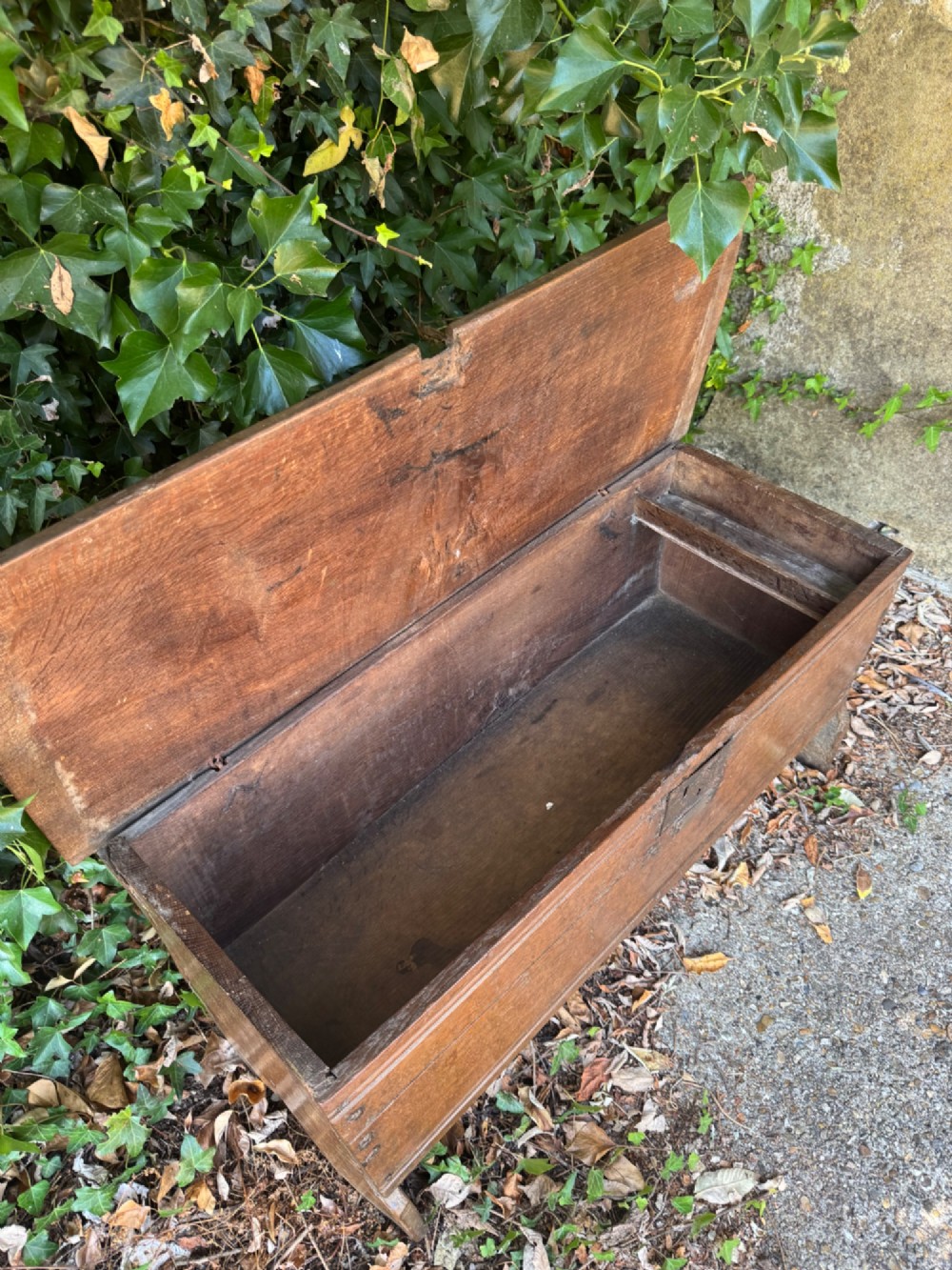 An early oak plank coffer featuring notched end panels, a hinged lid, horizontal moulding, and an iron lockplate. View IX