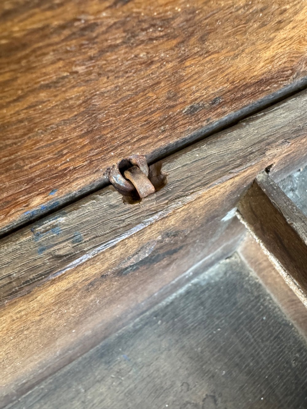 An early oak plank coffer featuring notched end panels, a hinged lid, horizontal moulding, and an iron lockplate. View X
