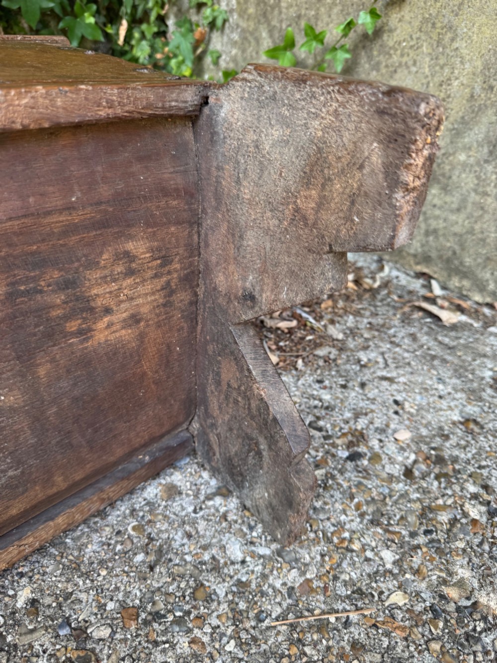 An early oak plank coffer featuring notched end panels, a hinged lid, horizontal moulding, and an iron lockplate. View XIII
