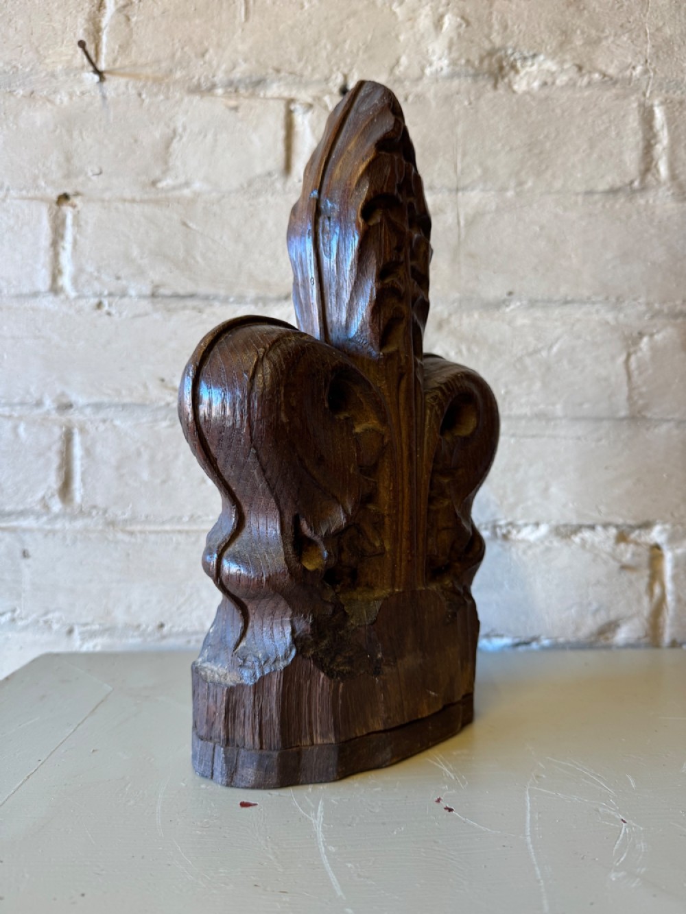 A hand-carved dark oak poppy head finial featuring intricate Gothic leaf motifs standing vertically. View III