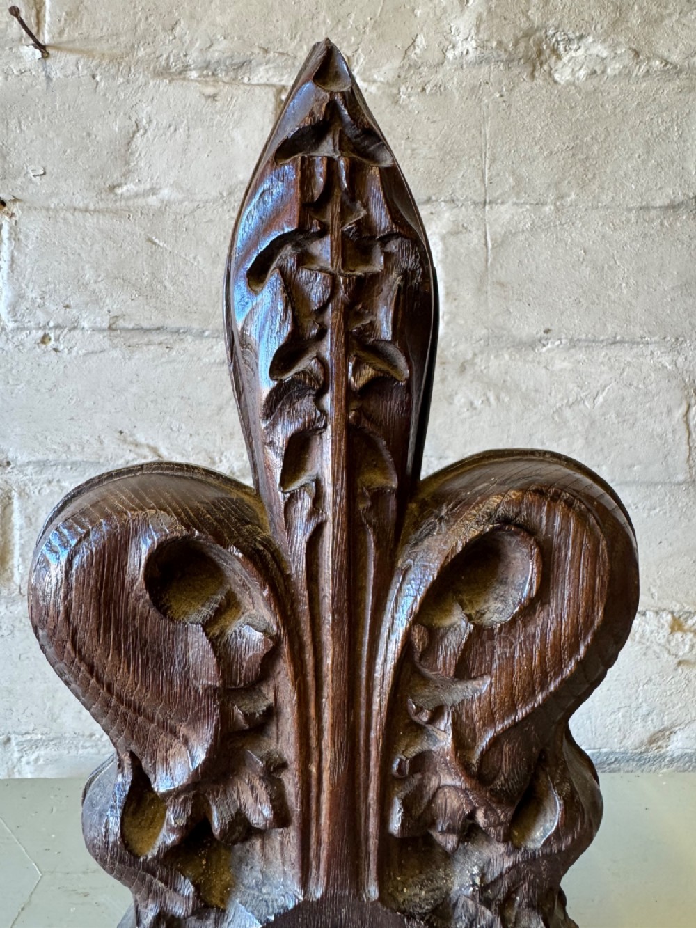 A hand-carved dark oak poppy head finial featuring intricate Gothic leaf motifs standing vertically. View V