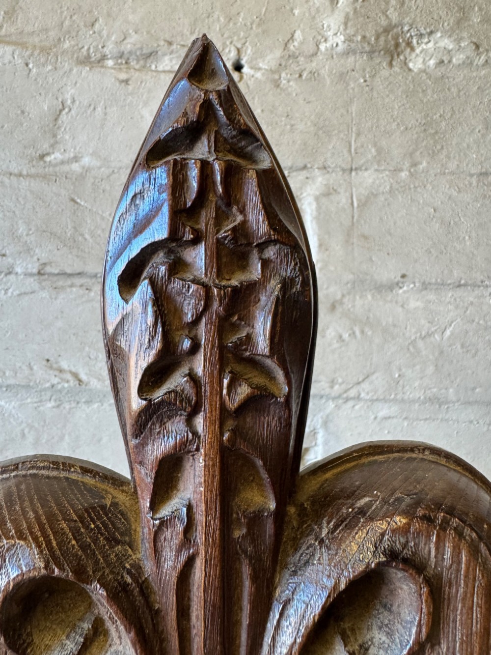 A hand-carved dark oak poppy head finial featuring intricate Gothic leaf motifs standing vertically. View VII