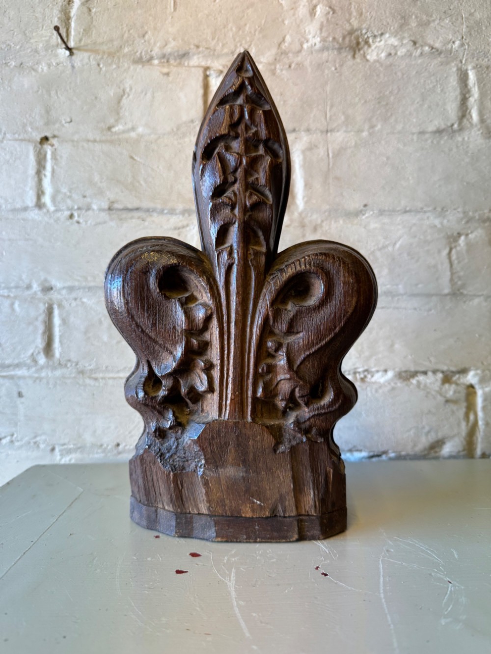 A hand-carved dark oak poppy head finial featuring intricate Gothic leaf motifs standing vertically. View X