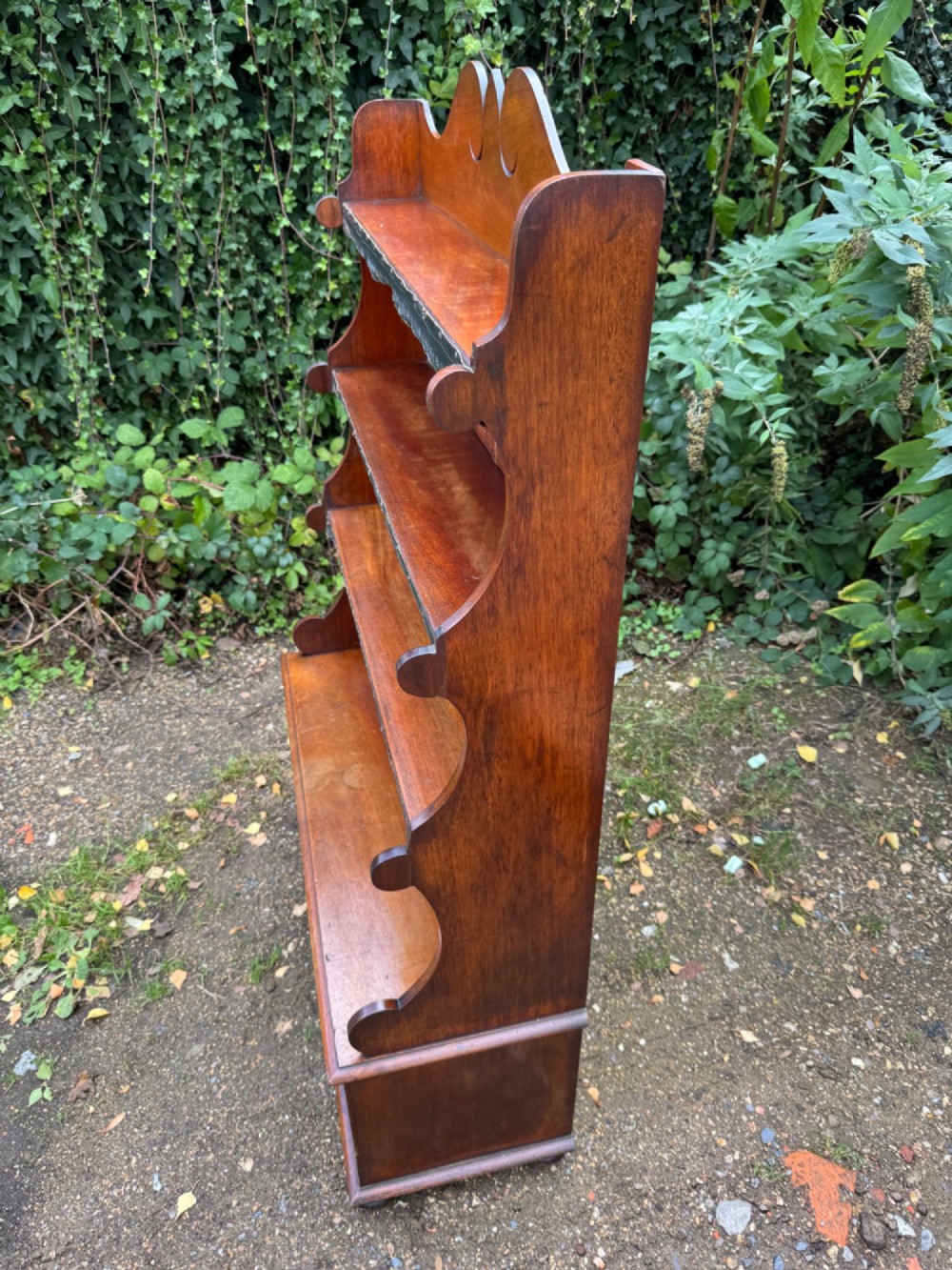 An antique mahogany waterfall bookcase featuring four open graduated shelves with dark trim above two lower drawers with turned wood knobs. View XIII