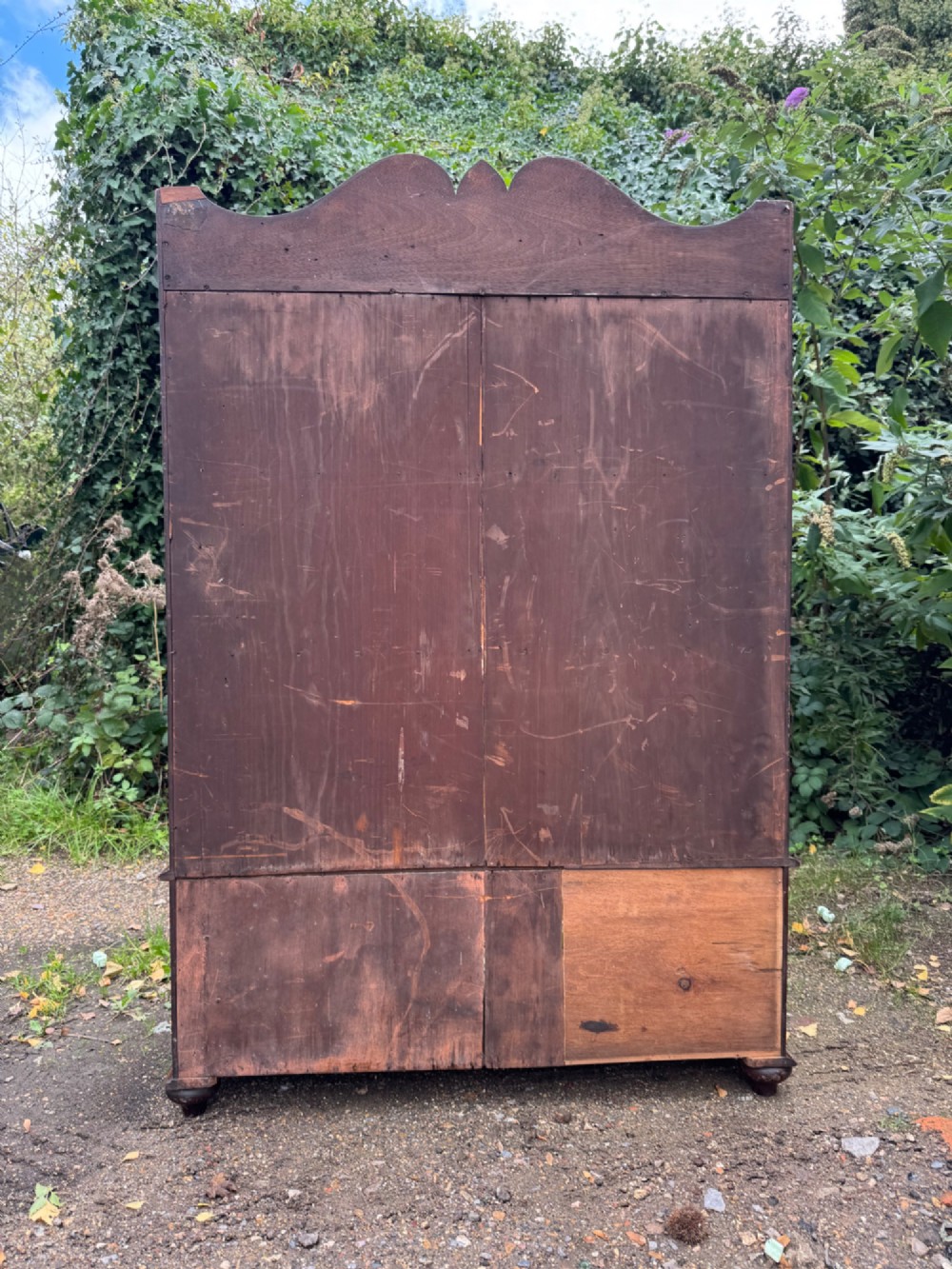 An antique mahogany waterfall bookcase featuring four open graduated shelves with dark trim above two lower drawers with turned wood knobs. View XIV