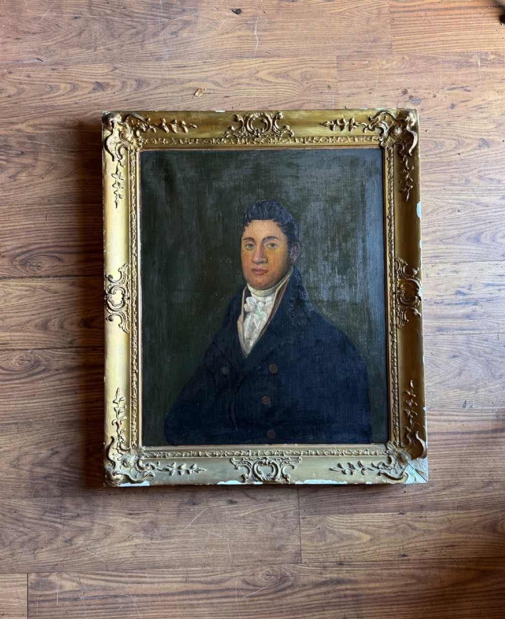 An antique oil painting depicting a gentleman in a dark double-breasted coat and white cravat, set within an ornate gold giltwood frame.