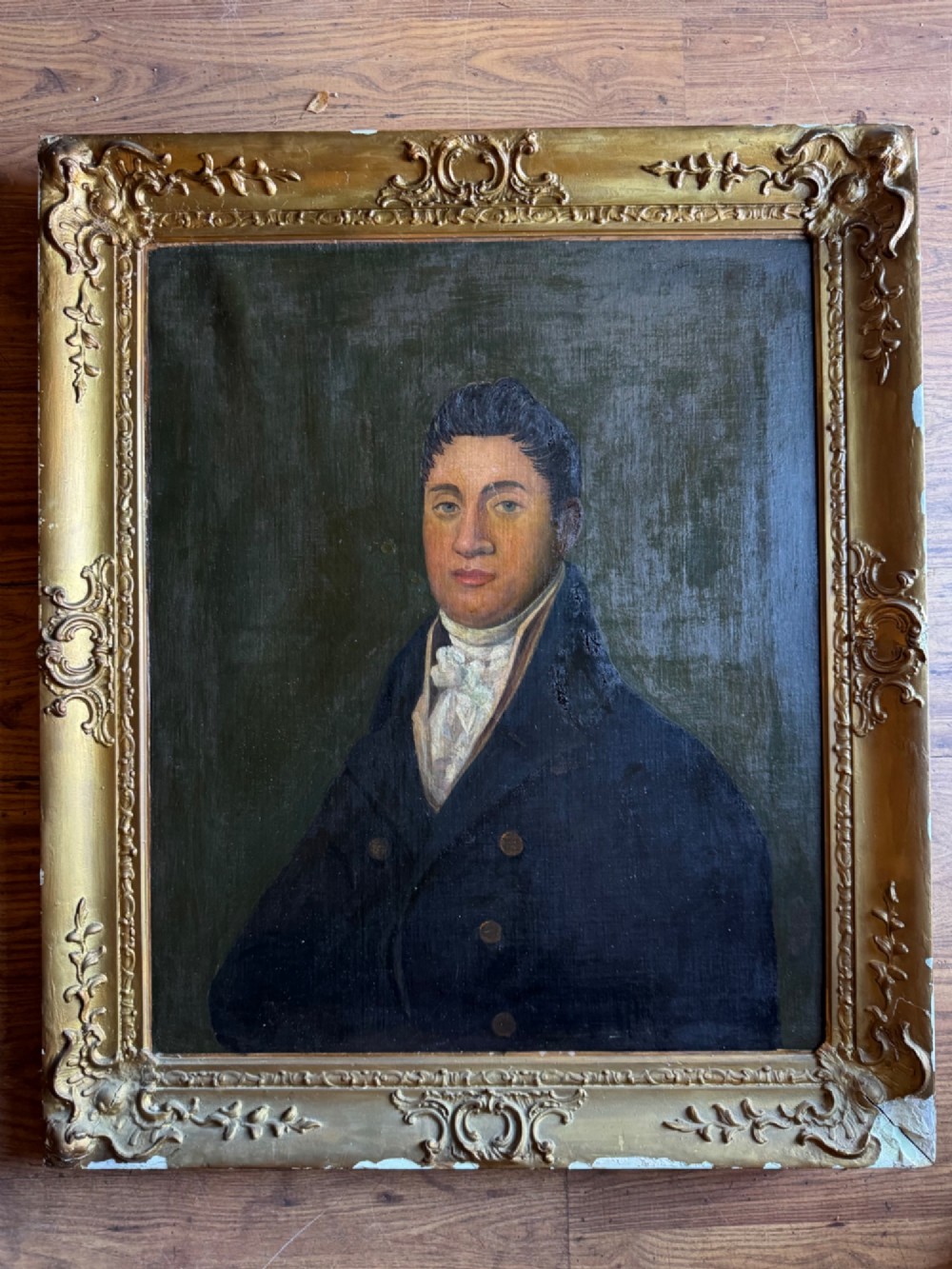 An antique oil painting depicting a gentleman in a dark double-breasted coat and white cravat, set within an ornate gold giltwood frame. View II