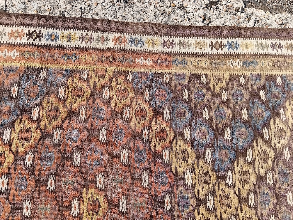 A long handwoven wool kilim runner rug with a repeating geometric diamond lattice pattern in terracotta brown and neutral tones. View III