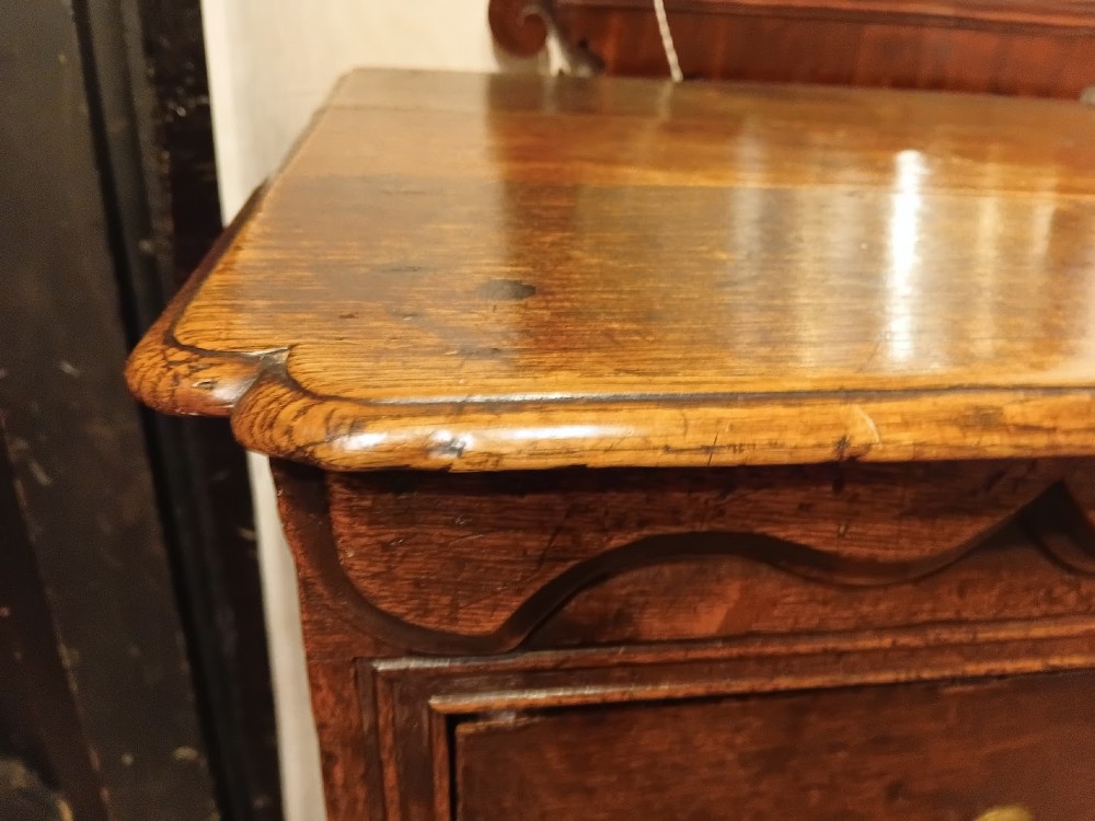 An antique brown oak chest of drawers featuring three small upper drawers over three long graduated drawers with brass drop handles. View II