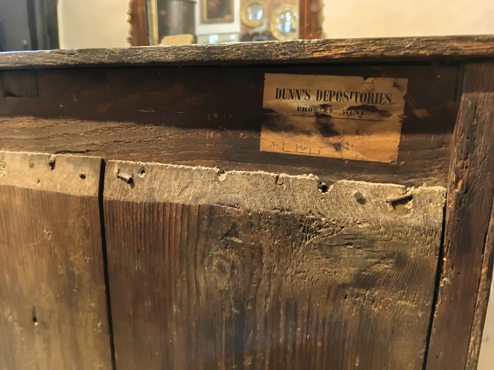 An antique brown oak chest of drawers featuring three small upper drawers over three long graduated drawers with brass drop handles. View VI