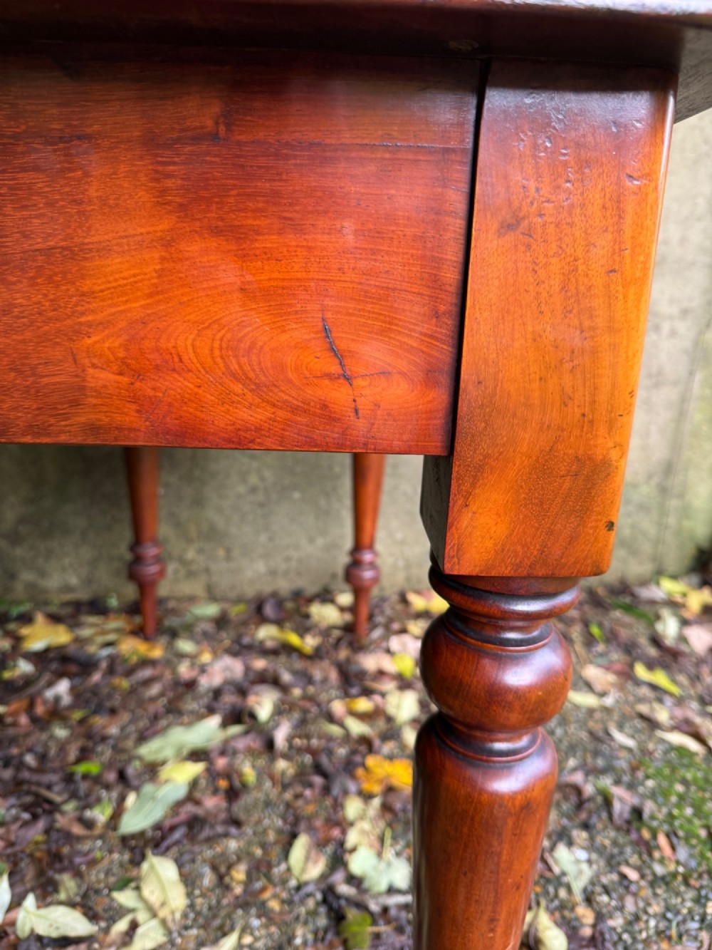 An antique reddish-brown mahogany writing table featuring two drawers with wooden knob handles, turned legs, and a three-sided raised rear gallery. View XIII