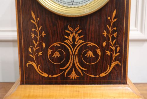 fig 3. A nineteenth-century rectangular dark rosewood mantel clock featuring foliate marquetry inlay, a brass-rimmed circular dial with Roman numerals, and a stepped plinth base.