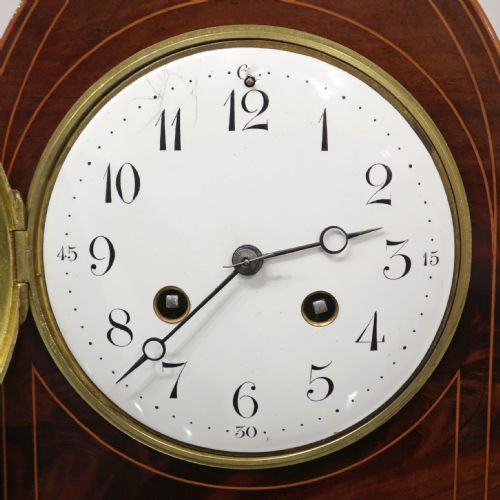 fig 1. A French Belle Epoque arched mahogany mantel clock featuring a white enamel dial, brass bezel, and fine stringing inlay.