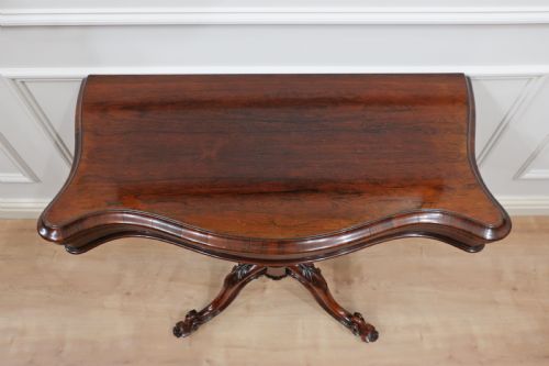 fig 2. A Victorian dark brown rosewood side table featuring a serpentine top, central turned column, and four carved scroll legs.