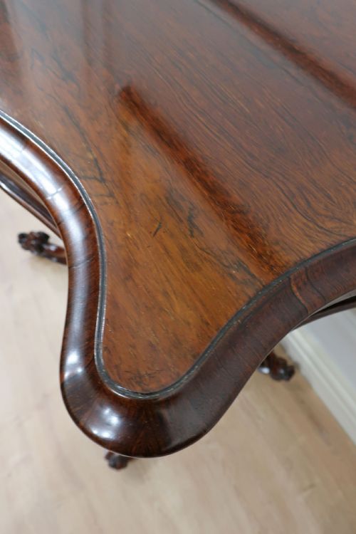 fig 3. A Victorian dark brown rosewood side table featuring a serpentine top, central turned column, and four carved scroll legs.
