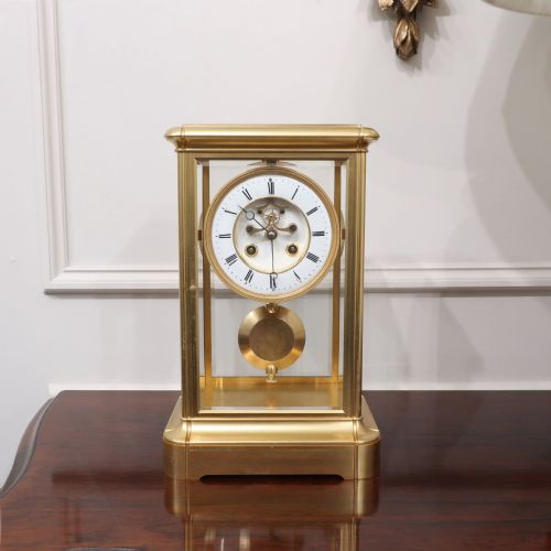 fig 1. A rectangular French gilt brass mantel clock featuring four bevelled glass panels, an exposed pendulum, and a white enamel dial with Roman numerals.