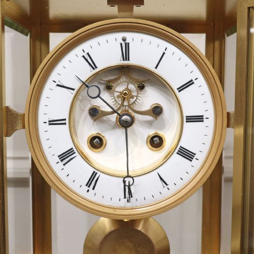 fig 2. A rectangular French gilt brass mantel clock featuring four bevelled glass panels, an exposed pendulum, and a white enamel dial with Roman numerals.