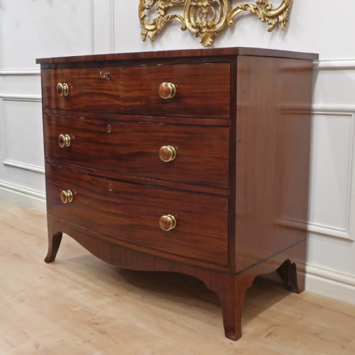 fig 2. A Georgian bow-fronted mahogany chest of drawers featuring three graduated drawers with circular brass knob handles and splayed bracket feet.