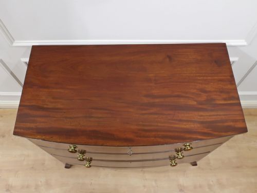 fig 3. A Georgian bow-fronted mahogany chest of drawers featuring three graduated drawers with circular brass knob handles and splayed bracket feet.
