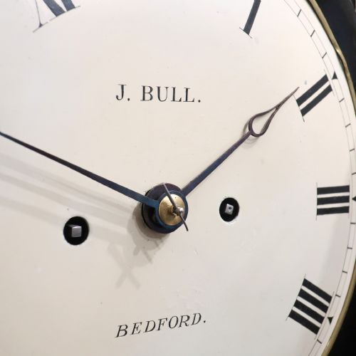 fig 3. An ebonised William IV bracket clock featuring brass inlays, a pineapple finial, lion mask side handles, ball feet, and a white circular dial with Roman numerals signed J. Bull Bedford.