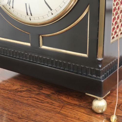 fig 4. An ebonised William IV bracket clock featuring brass inlays, a pineapple finial, lion mask side handles, ball feet, and a white circular dial with Roman numerals signed J. Bull Bedford.
