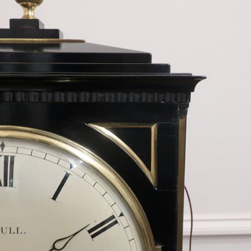 fig 6. An ebonised William IV bracket clock featuring brass inlays, a pineapple finial, lion mask side handles, ball feet, and a white circular dial with Roman numerals signed J. Bull Bedford.