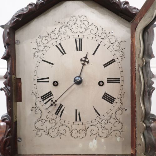 fig 2. An early Victorian mahogany library clock featuring a heavily carved leafy frame, Roman numeral dial face, and stepped side moulding.