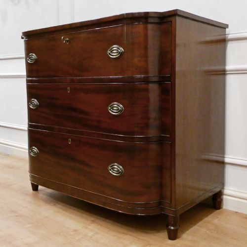fig 1. A Regency period mahogany bow-fronted chest of drawers featuring three graduated drawers with brass oval handles and short turned feet.