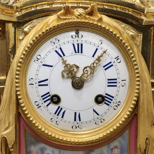 fig 2. A French gilt bronze mantel clock featuring an urn top finial, pink hand-painted porcelain panels, and a white enamel dial with Roman numerals.