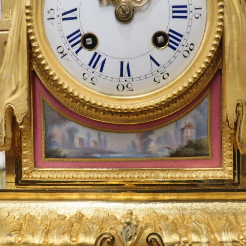 fig 3. A French gilt bronze mantel clock featuring an urn top finial, pink hand-painted porcelain panels, and a white enamel dial with Roman numerals.