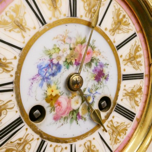 fig 3. A French Louis XV style gilt bronze mantel clock featuring a hand-painted porcelain dial, lower cherub panel, scroll feet, and an ornamental urn finial.