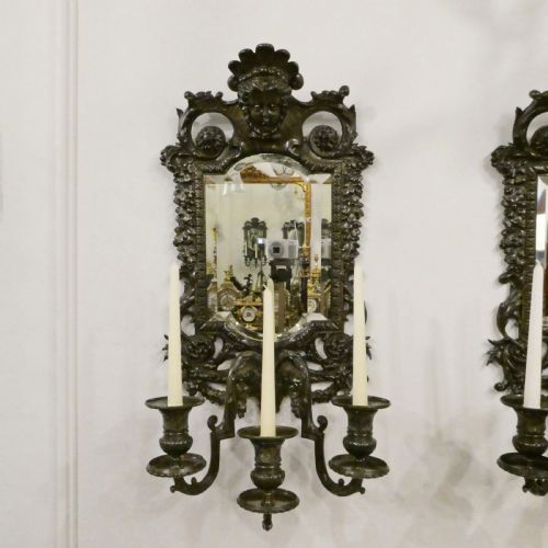 fig 1. A pair of dark patinated bronze wall girandoles with ornate foliate frames surrounding central mirrored plates and three candle branches each.