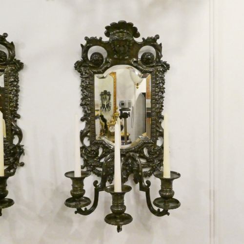 fig 2. A pair of dark patinated bronze wall girandoles with ornate foliate frames surrounding central mirrored plates and three candle branches each.