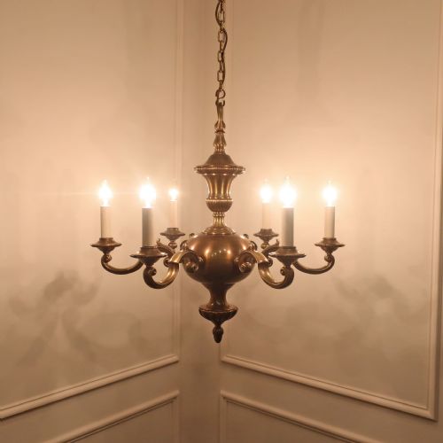 fig 1. An Edwardian brass six-arm chandelier hanging from a link chain, featuring curved S-scroll branches and candle-style bulb holders.