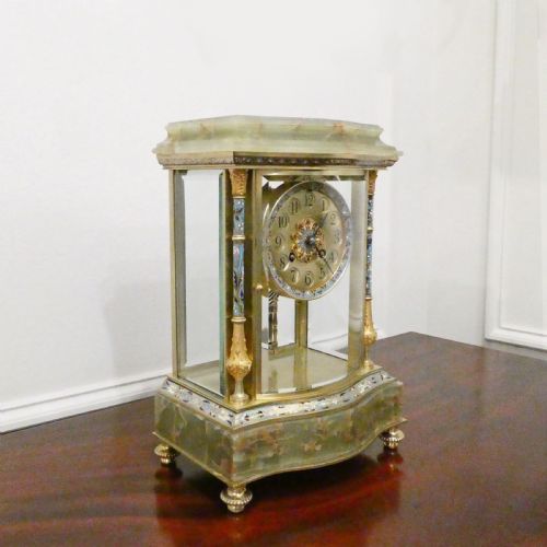 fig 1. An antique French four-glass mantel clock featuring green onyx bases, champleve enamel columns, and a visible brass movement.