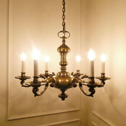fig 1. An Edwardian six-light aged brass chandelier featuring a central turned baluster shaft, scrolled arms, and candle sleeves.