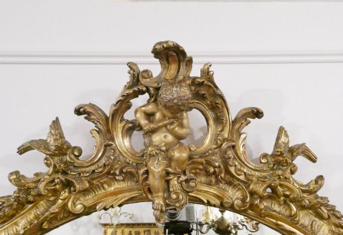 fig 1. A 19th-century French Louis XVI style gilded wall mirror featuring a carved decorative crest and beaded frame border.