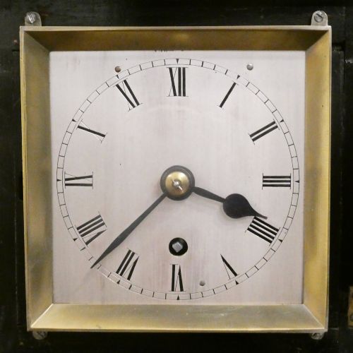 fig 2. An early Victorian ebonised wooden library clock featuring a square dial with Roman numerals, side viewing apertures, and brass accents.