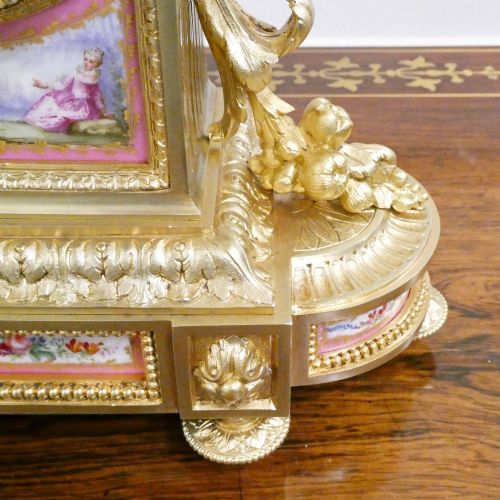 fig 4. A Louis XVI style gilt bronze mantel clock featuring hand-painted pink porcelain panels and an urn-shaped finial.