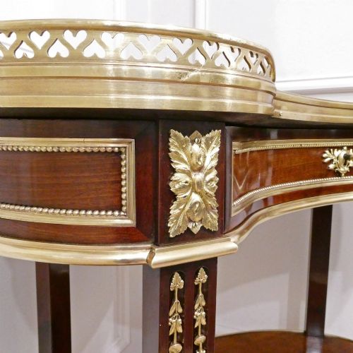 fig 3. A French Louis XVI style kidney-shaped mahogany side table featuring a marble top, pierced brass gallery, lower undertier, and elaborate gilt-bronze mounts.