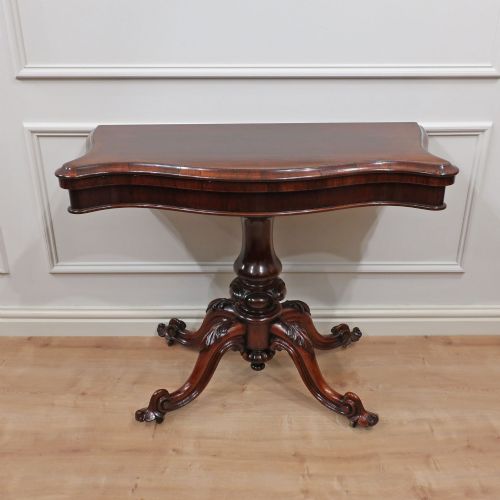 fig 2. A Victorian rosewood side table featuring a serpentine fold-over top mounted on a central carved pedestal with four scroll-footed legs.