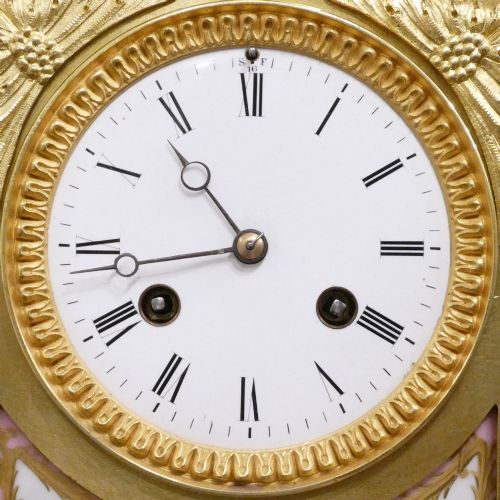 fig 2. An antique French gilt bronze mantel clock featuring hand-painted pink porcelain panels, a porcelain urn finial, and an enamel dial with Roman numerals.