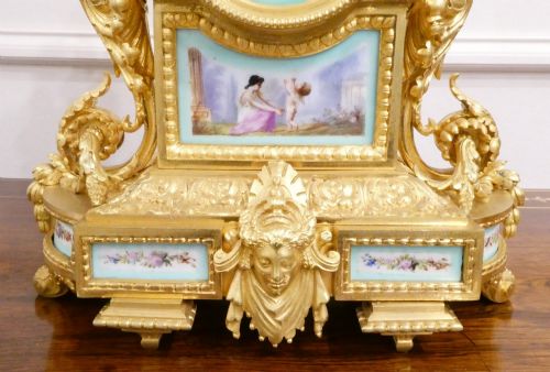 fig 3. A French 19th-century gilt bronze mantel clock featuring light blue hand-painted porcelain panels, sculpted putti, an urn finial, and an enamel Roman numeral dial.